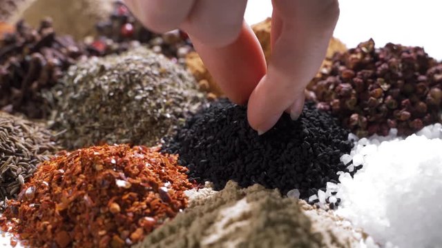 Human hand holds and press a pinch of a black cumin by a hand over