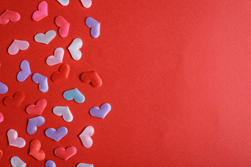 many multi-colored hearts on red background with copy space
