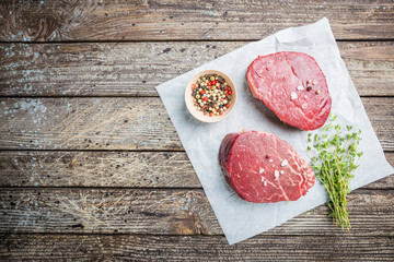 Raw marbled meat steak Filet Mignon with seasonings over stone background, top view.
