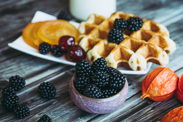Petit déjeuner sain avec lait gaufre mûres du jardin et fruits confits	