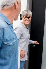 cropped view of mature man looking at smiling woman near new house