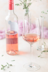Glass and bottle of rose wine on light background.