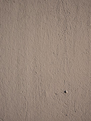 Rough texture of light brown stucco on the wall.