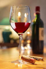 Rotweinglas und Flasche im Kerzenlicht