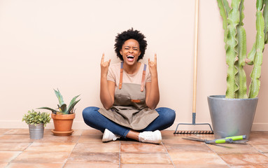 Gardener woman sitting on the floor making rock gesture