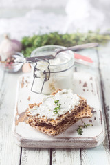 Crispbread toast with homemade herb and garlic cottage cheese on wooden background