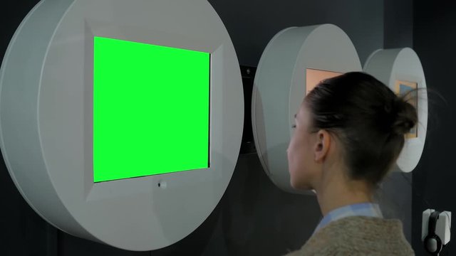 Green screen, mock up, future, copyspace, template, chroma key, technology concept. Woman looking at blank digital interactive green display wall at exhibition, museum with futuristic sci-fi interior