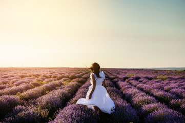 Fototapeta na wymiar back view of a woman in white dress in lavander field