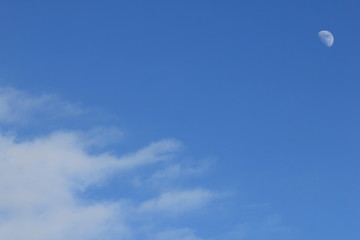 Blue sky and white half moon and white clouds