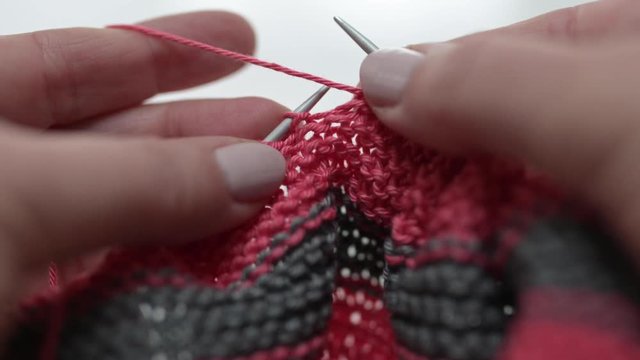 Nahaufnahme von weiblichen H&auml;nden, die aus rosa, magenta Wolle aus Baumwolle mit Stricknadel stricken.