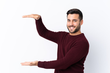 Young handsome man with beard over isolated white background holding copyspace to insert an ad