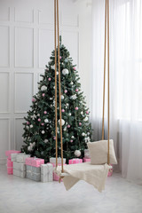 Dressed up Christmas tree near the fireplace in the apartment. Christmas decor with Christmas tree