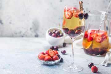 White wine sangria or punch with berries and ice in glass and pincher. Homemade refreshing fruit sangria.