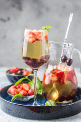 White wine sangria or punch with berries and ice in glass and pincher. Homemade refreshing fruit sangria.