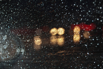 Rainy weather. Rain water drops on a window glass. Blurred background. Night and rain. Rain on...