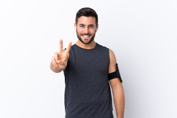 Young sport handsome man with beard over isolated white background smiling and showing victory sign