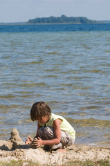 Girl on beach builds towers of sand