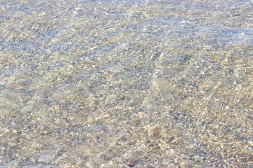 clear sea water through which the sandy bottom is visible