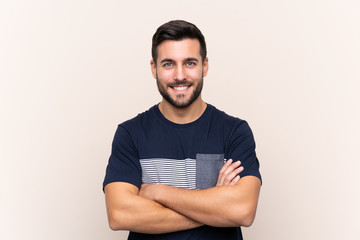 Young handsome man with beard over isolated background keeping the arms crossed in frontal position