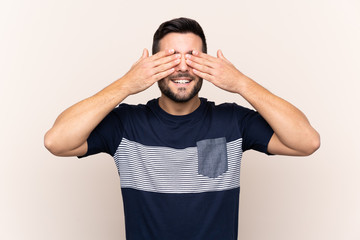 Young handsome man with beard over isolated background covering eyes by hands