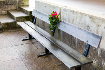 A bunch of flowers attached to a bench to mark the memory of a lost loved one