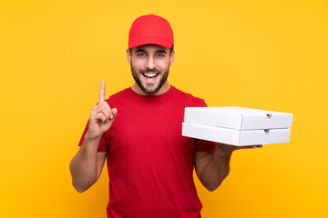pizza delivery man with work uniform picking up pizza boxes over isolated yellow background...