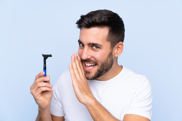 Young handsome man shaving his beard over isolated background whispering something