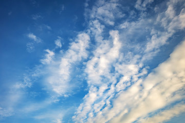 blurred dark sky background with evening fluffy curly rolling clouds with setting sun. Good windy weather