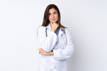 Teenager girl over isolated white background wearing a doctor gown and thinking