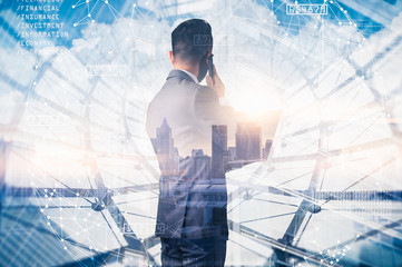 The double exposure image of the businessman standing back during sunrise overlay with cityscape image. The concept of modern life, business, city life and internet of things.