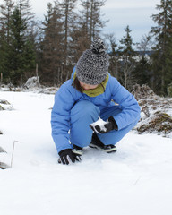 Fototapeta na wymiar young winter child touching snow, sitting on the ground