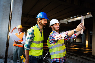 Two satisfied engineers talking at building site with construction structure in background