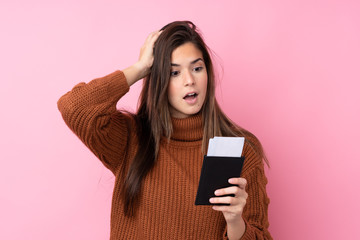 Naklejka premium Teenager girl over isolated pink background in vacation with plane tickets and surprised