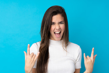 Teenager girl over isolated blue background making rock gesture