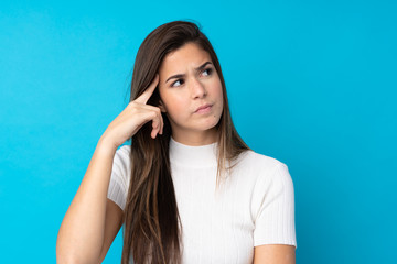 Fototapeta premium Teenager girl over isolated blue background making the gesture of madness putting finger on the head