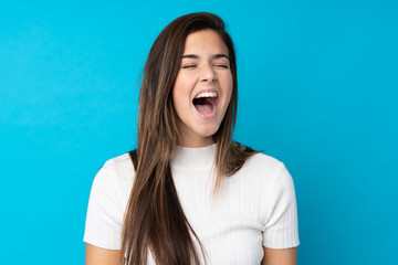 Teenager girl over isolated blue background shouting to the front with mouth wide open