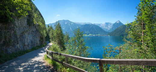 idyllic walkway and bike route along lake achensee east side in mountain landscape austria - obrazy, fototapety, plakaty