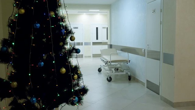 Medical clinic at holidays. Christmas tree and empty gurney in hallway in modern hospital. 4K