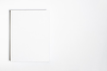 Mockup of closed blank square book at white textured paper background