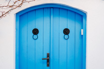 Old blue door on a white wall of a house.