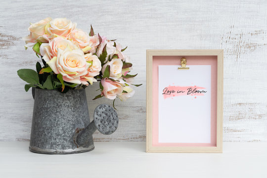 Mockup Still life Picture frame and at watering can with Bouquet of roses on grunge white wood. Valentines Day Background concept. Mock up with photo frame for your picture or text