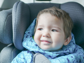 The child does not like to ride in a car seat. Dissatisfied child in a car seat. Preschool cute boy 1-2 years old, sitting in a safe car seat and crying during a family trip by car, bad mood, negative