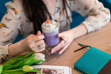 purple coffee in the hands of a girl on a beige background