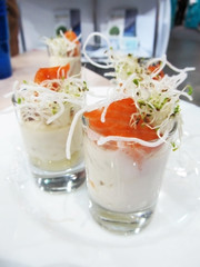 Elegant buffet appetizer with salmon and microgreen in small transparent cups on a white plate. Delicious appetizer with selective focus. Food and restaurant, sale, menu concept.