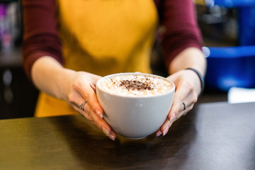 cappuccino with milk in a white mug on a brown background