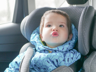 grimacing child in a car seat. Child safety in the child's car seat during sleep.