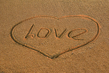 Heart and the word love drawn on the sand. The beach background. Close up. Valentine's day 