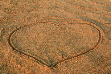 A heart drawn in the sand. The beach background. Close up