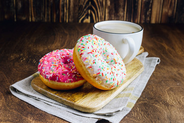 Colorful Donuts breakfast composition with different color styles of doughnuts and fresh coffee on wooden background. Selective focus