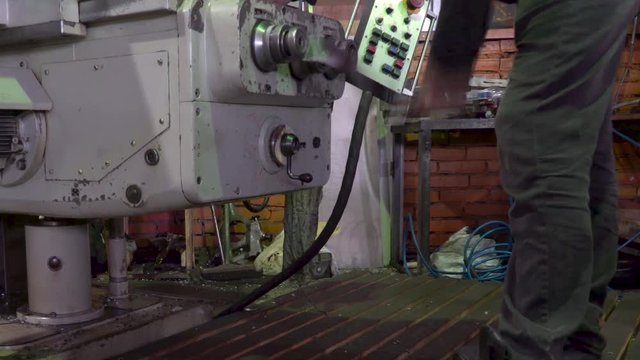 Close up of unrecognizable machine operator turning handle of machine while adjusting it. Stock footage. Side view of a worker turning milling machine control handle.